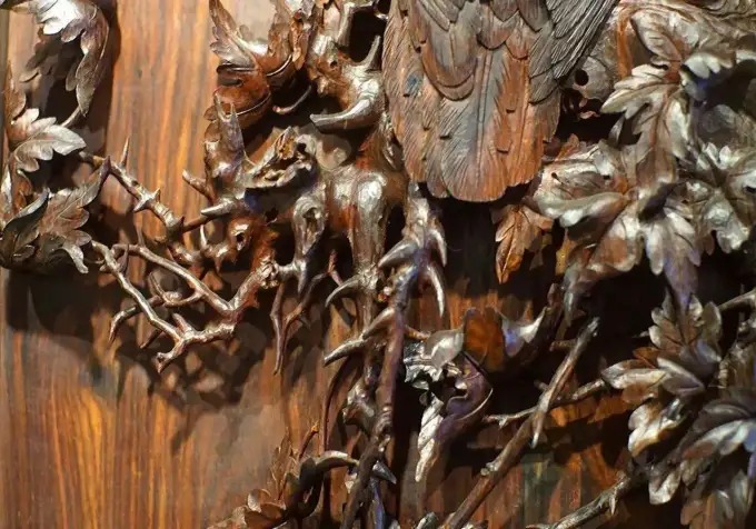 Detalhe de figuras e folhagens cuidadosamente entalhadas em madeira