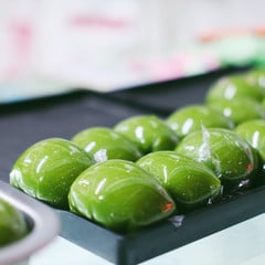 Glossy green qingtuan on a black tray